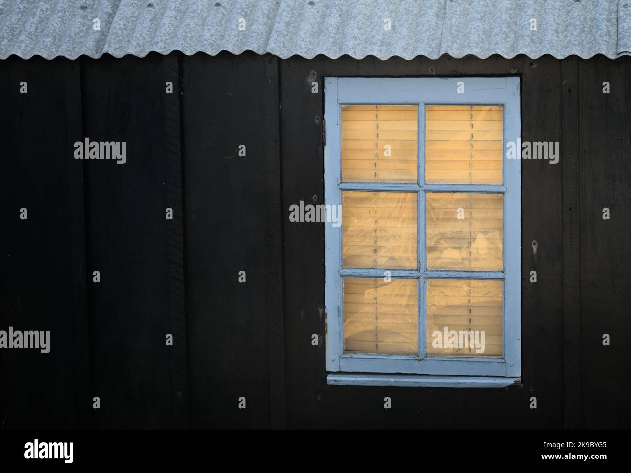 Fenster mit Jalousien in Einer Pitch Painted Wooden Shack, Hengistbury UK Stockfoto