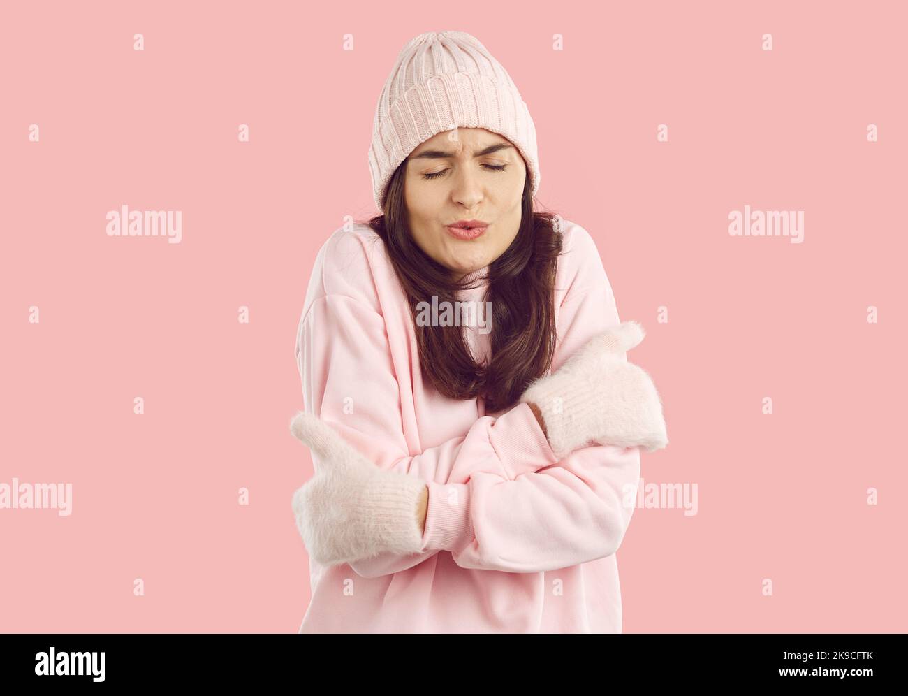 Frau in warmem Hut, Sweatshirt und Fäustlingen eiskalt und zitternd bei kaltem Winterwetter Stockfoto