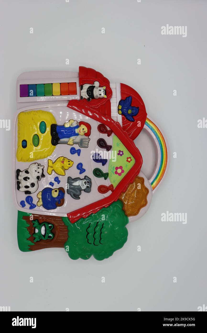 Elektrisches interaktives Spielzeug für Kinder oder Kleinkinder. Klangspielzeug in Form eines Bauernhauses mit Tieren, Landwirt und einem Baum auf weißem Hintergrund. Stockfoto