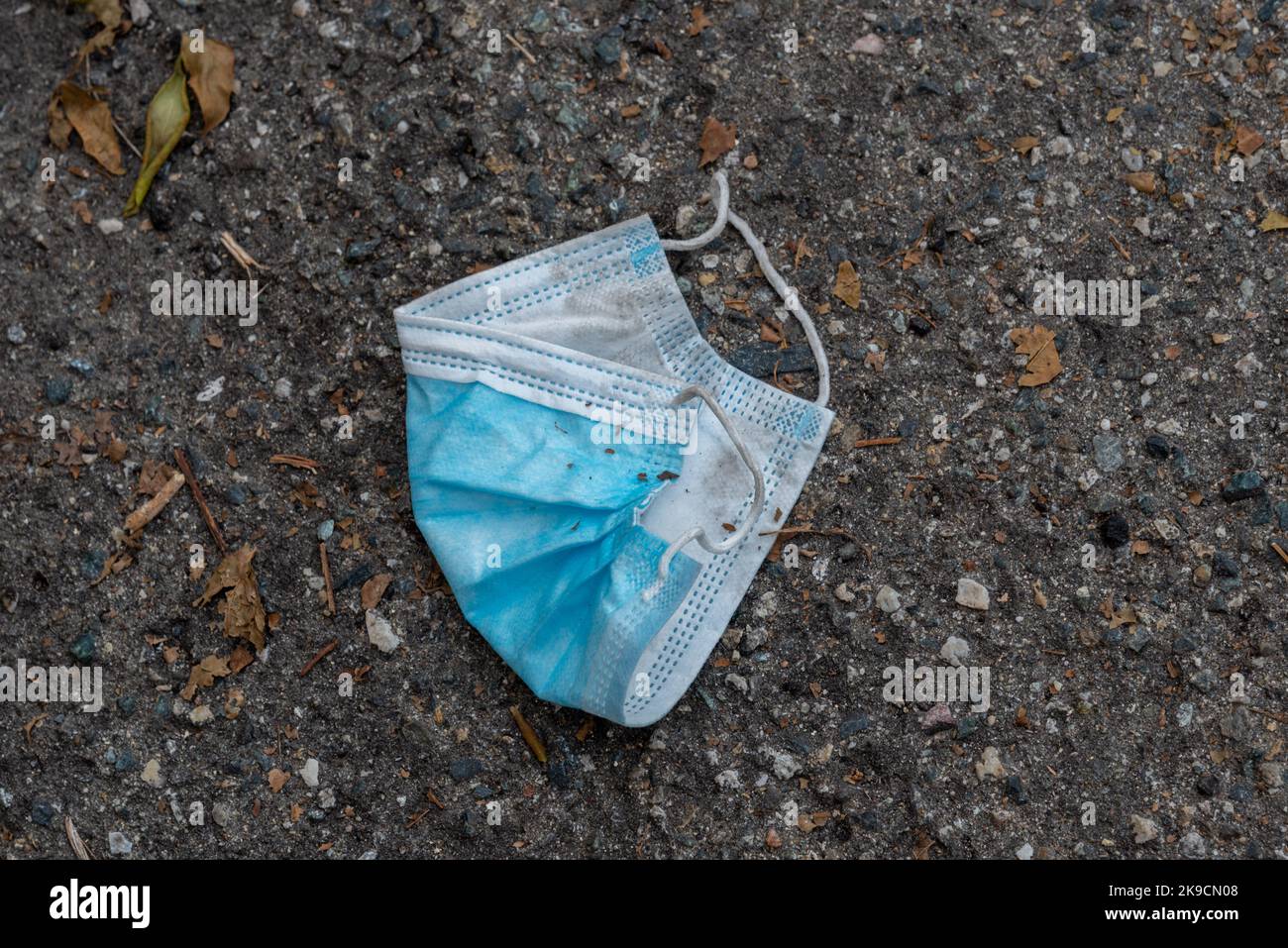 Gebrauchte chirurgische Maske auf der Straße weggeworfen, Symbol der Verschmutzung in Zeiten der Pandemie Stockfoto