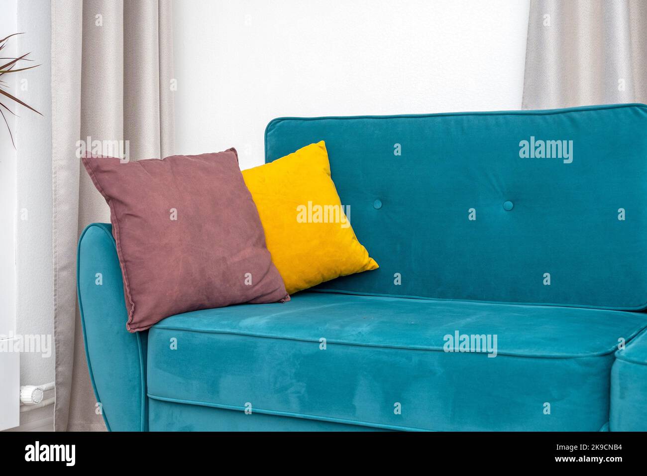 Hellgelbes Kissen auf blauem, türkisfarbenem Sofa oder Sofa, Interieur des komfortablen Wohnzimmers Stockfoto