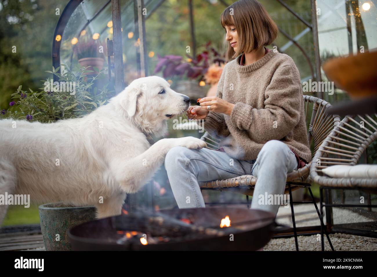 Frau mit Hund am Feuer im Hinterhof Stockfoto