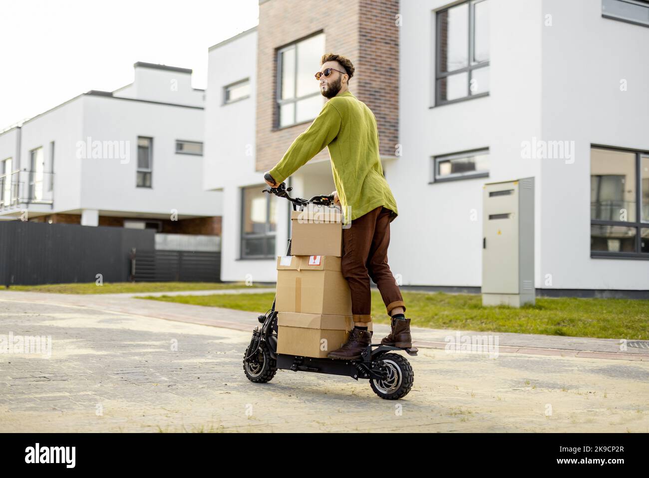 Mann fährt Elektroroller mit Papppackungen Stockfoto