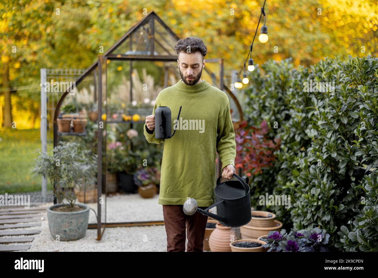 Stilvoller Kerl mit Gießkannen im Garten Stockfoto