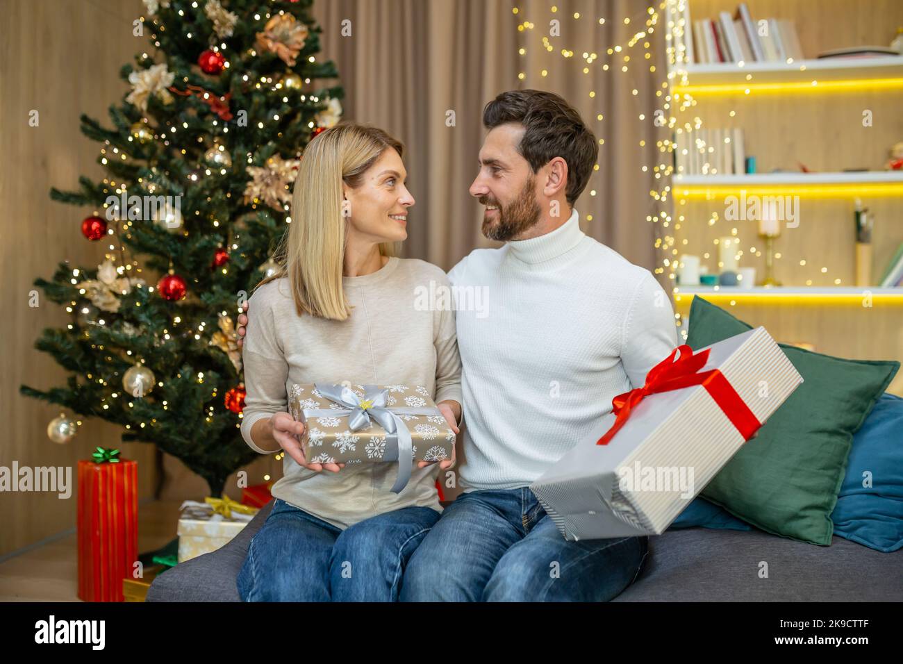 Ehepaar mittleren Alters tauscht Geschenke für weihnachten, Familie in der Liebe für weihnachten zu Hause sitzen auf dem Sofa zu Hause. Stockfoto