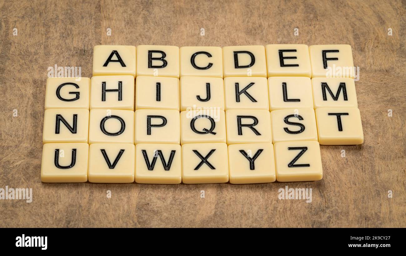Englisches Alphabet in Elfenbein Buchstaben Fliesen gegen texturiertes handgemachtes Papier Stockfoto