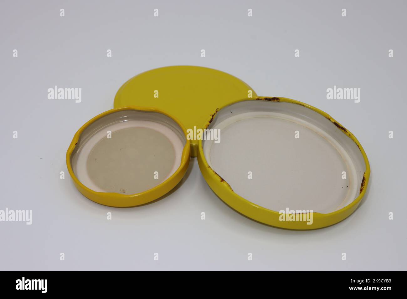 Alte gelbe Metall-Einmachglas Abdeckungen oder Glas Tassen auf einem weißen Hintergrund Stockfoto
