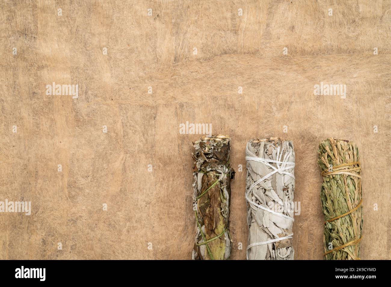 Weißer Salbei, Beifuß und siskiyou Zedernholz-Räucherstäbchen auf einem strukturierten Rindenpapier mit einem Kopierraum, Aromatherapie-Konzept Stockfoto