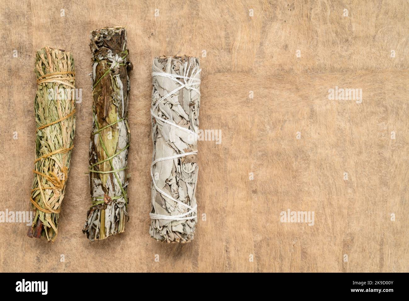 Weißer Salbei, Beifuß und siskiyou Zedernholz-Räucherstäbchen auf einem strukturierten Rindenpapier mit einem Kopierraum, Aromatherapie-Konzept Stockfoto