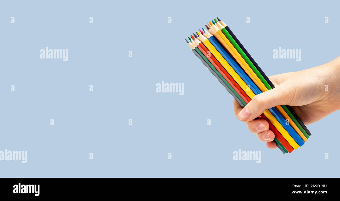 Bunte Stifte, farbige Materialien für Kunst in der Hand auf Werbebanner, blauer Promo-Hintergrund. Hochwertige Fotos Stockfoto