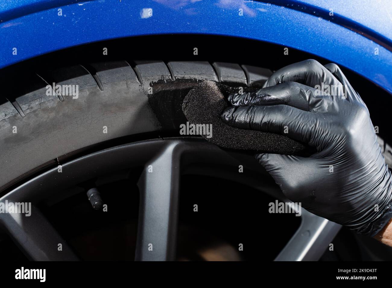 Schwärzung des Reifenrades des Autos mit Schwamm mit chemischer Schwärzung des Gummis in Detaillierung Auto-Service Stockfoto