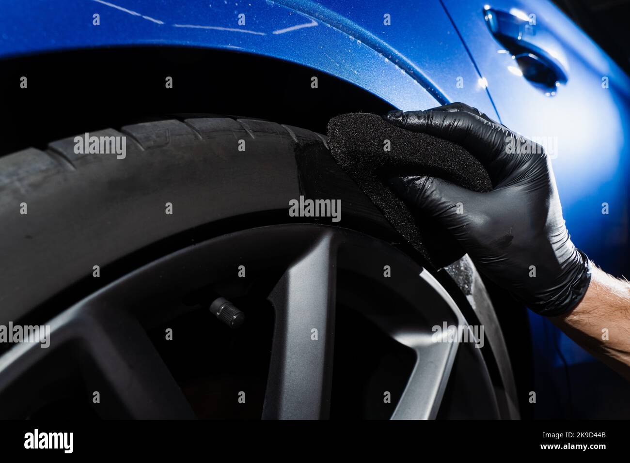 Schwärzung des Reifenrades des Autos mit Schwamm mit chemischer Schwärzung des Gummis in Detaillierung Auto-Service Stockfoto