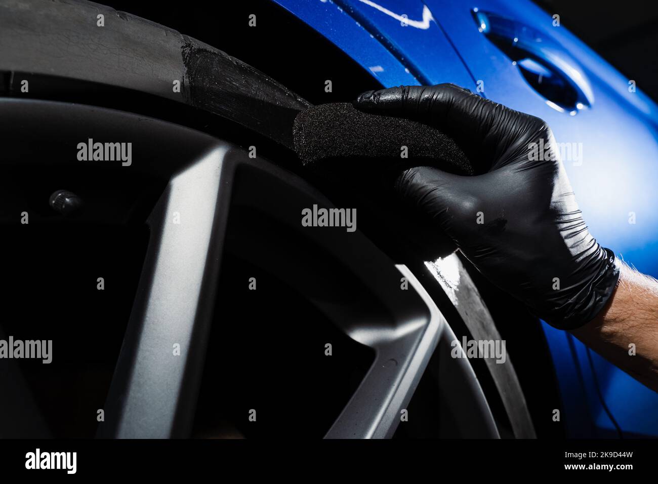 Schwärzung des Reifenrades des Autos mit Schwamm mit chemischer Schwärzung des Gummis in Detaillierung Auto-Service Stockfoto