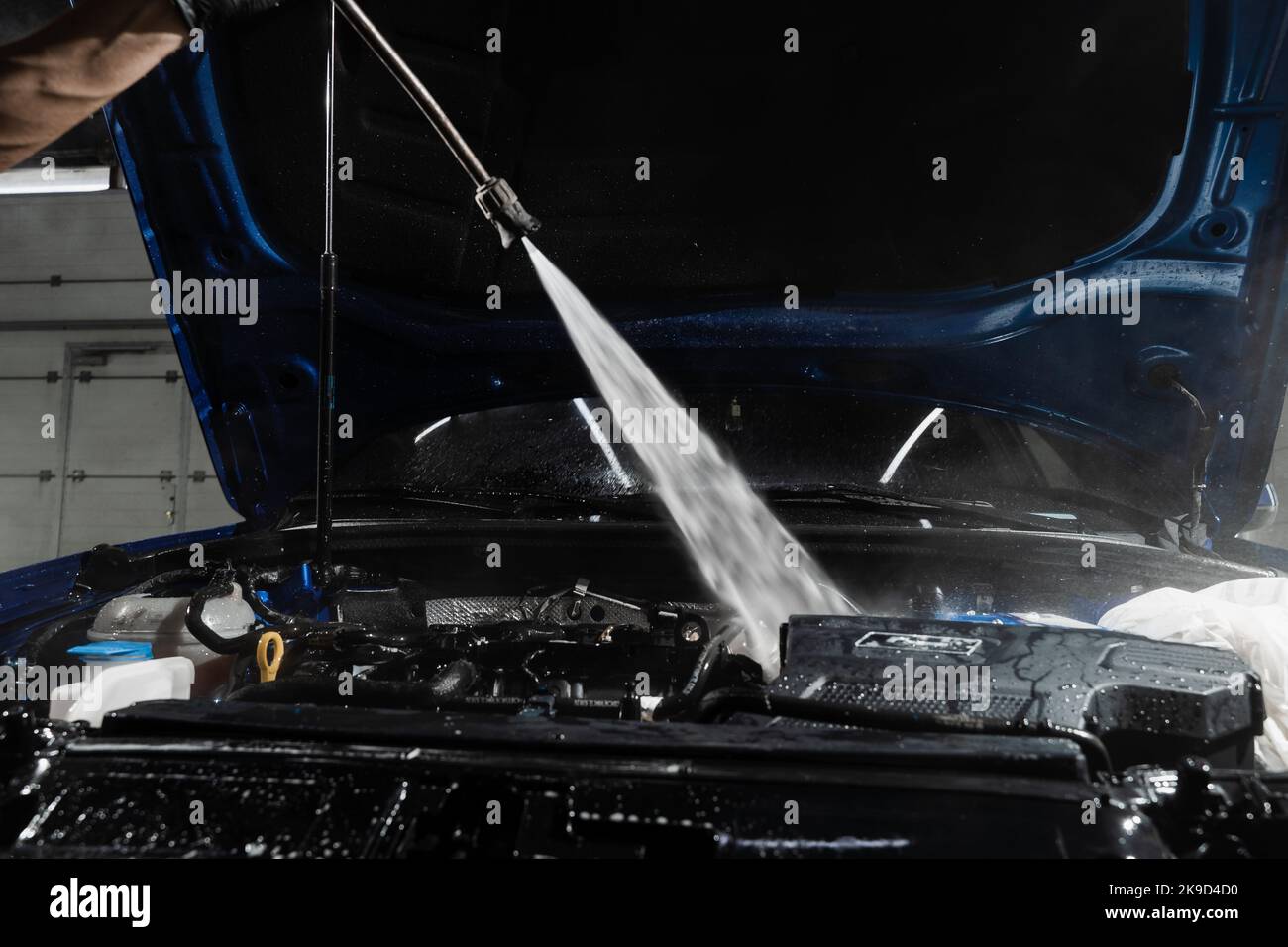 Waschen Auto-Motor mit Wasser in Detaillierung Auto-Service. Detaillierte Reinigung des Motors von Staub und Schmutz. Gießt Wasser auf den Motor des Autos Stockfoto