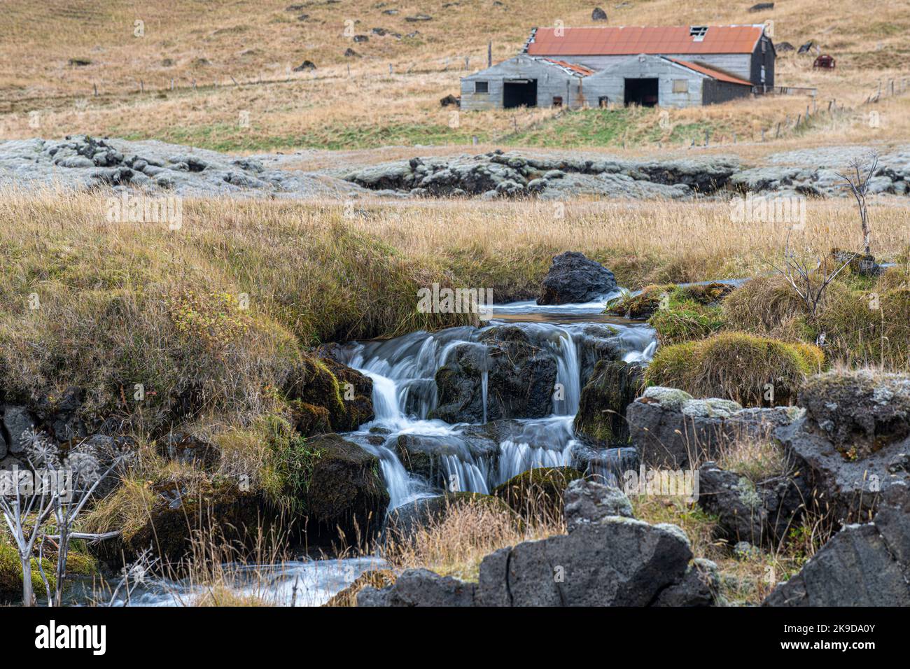 Wasserfall, Island mit altem Bauernhaus im Hintergrund Stockfoto