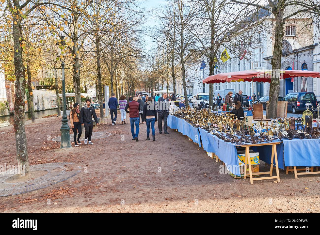 Touristen und Einheimische gehen früh am Morgen auf einem Flohmarkt auf De Dijver in Brügge, Flandern, Belgien, spazieren Stockfoto