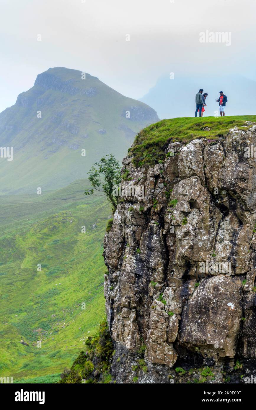 Trotternish, Isle of Skye, Schottland, Großbritannien-25 2022. Juli: An einem späten Sommernachmittag stehen Touristen nahe dem Rand einer riesigen, schieren Felswand und machen Fotos Stockfoto