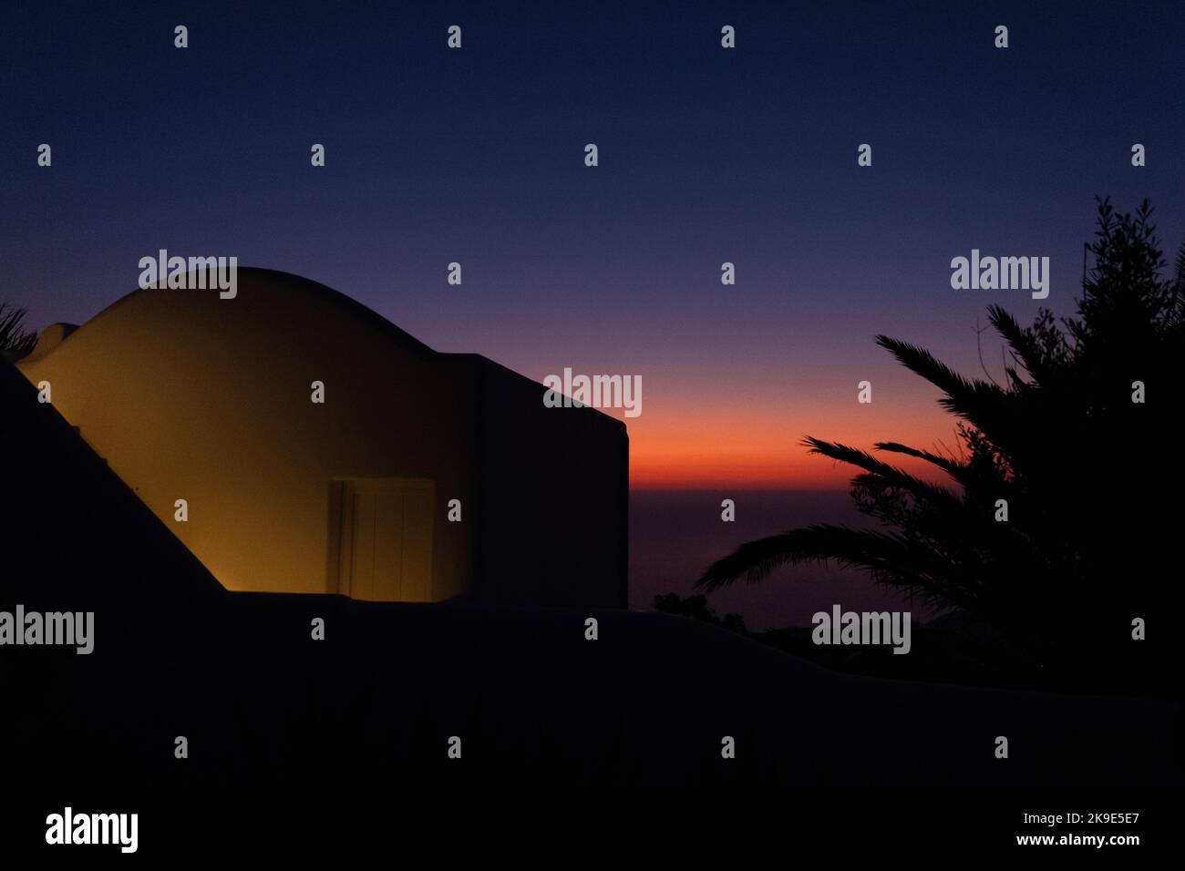 Sonnenaufgang über dem Meer. Blick auf ein Haus und einen Baum im Schatten. Stockfoto
