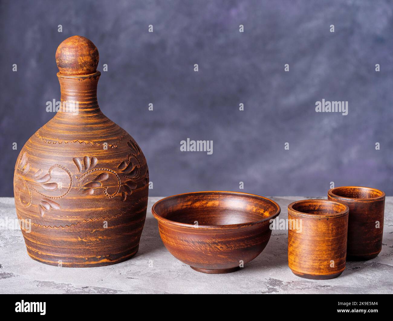 Tonkrug, Schüssel und zwei leere Keramikbecher auf einem grunge-Stil Hintergrund Stockfoto