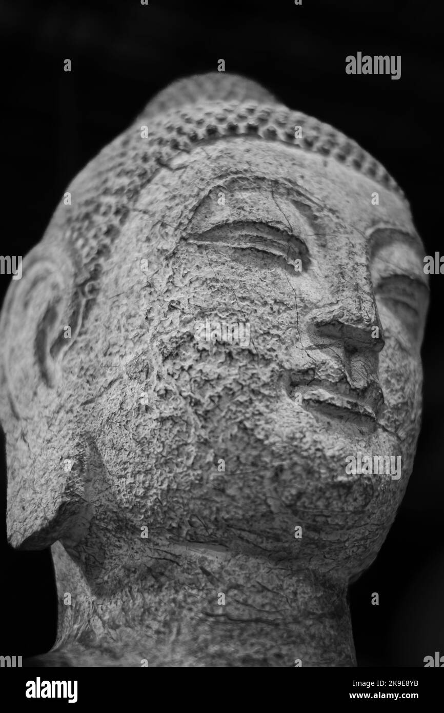 Budha Gesicht aus der Nähe. Nahaufnahme eines buddha-Kopfes auf schwarzem Hintergrund. Bhuddha Statue aus Stein. Niemand, Reisefoto Stockfoto