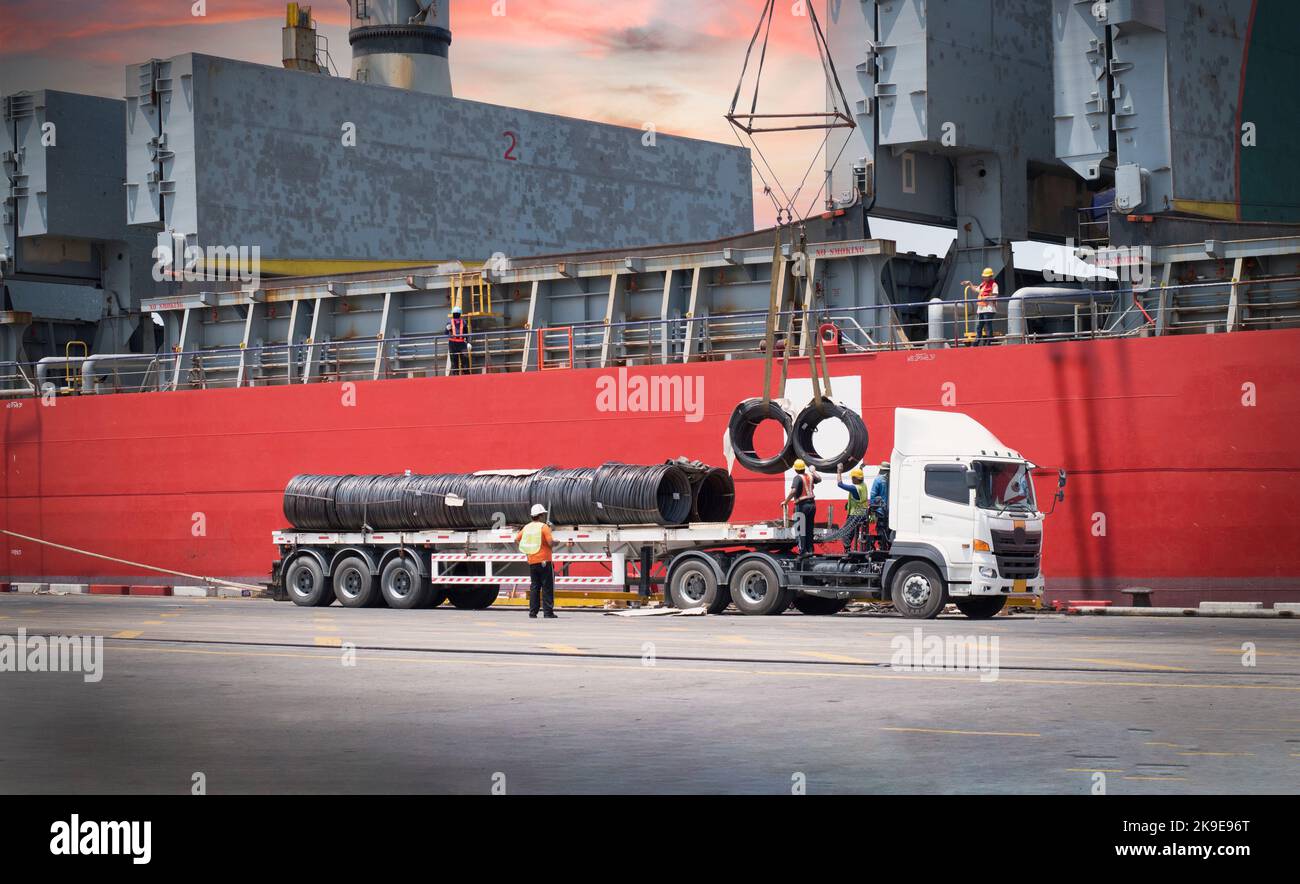 Frachtschiff entlädt Stahldraht am Hafenterminal. LKW verladen Stahlgut am Seehafen. Transport und Handling der Stückgutlogistik. Operat Stockfoto