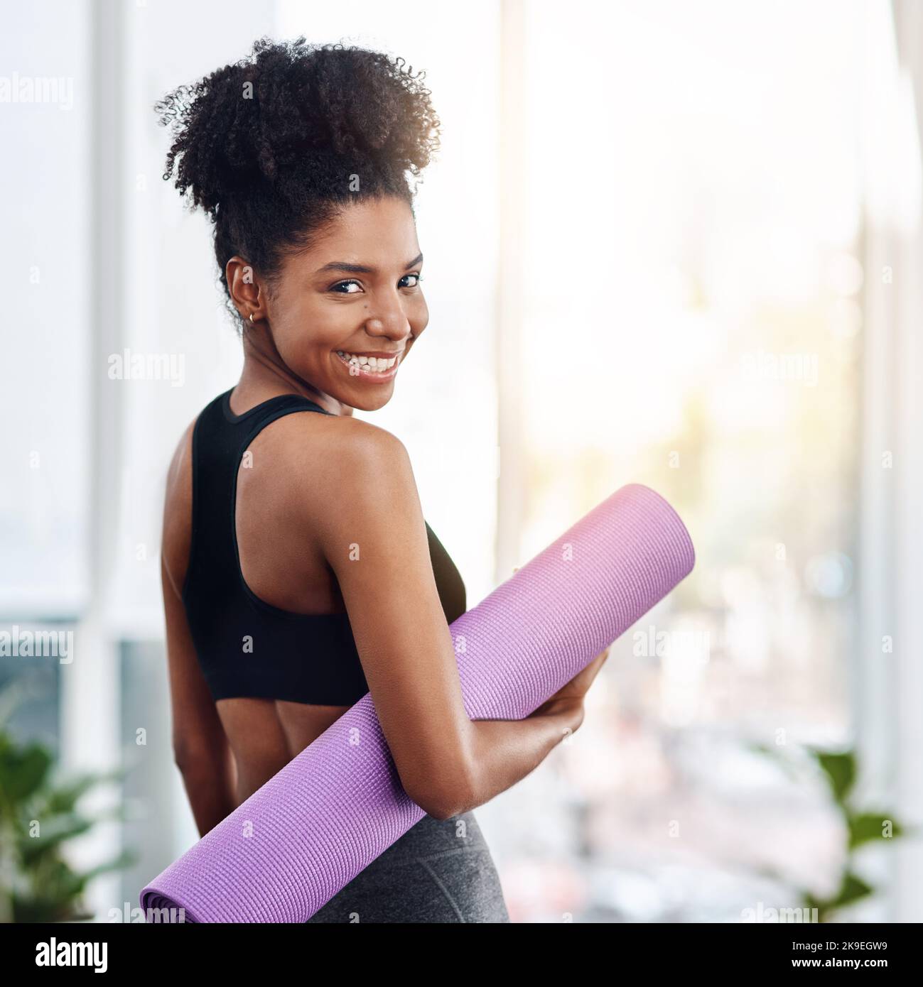 Widmen Sie sich mehr der Liebe. Eine attraktive junge Frau, die ihre Yogamatte hält. Stockfoto