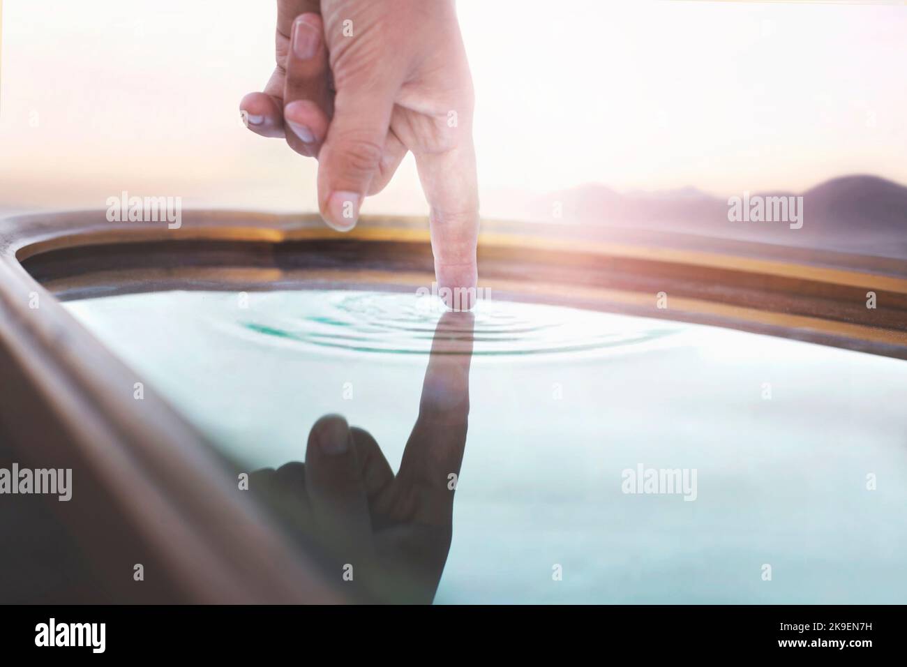 Person, die eine Wasserquelle berührt, die sich in einem Spiegel widerspiegelt, Konzept der Quelle des Lebens Stockfoto