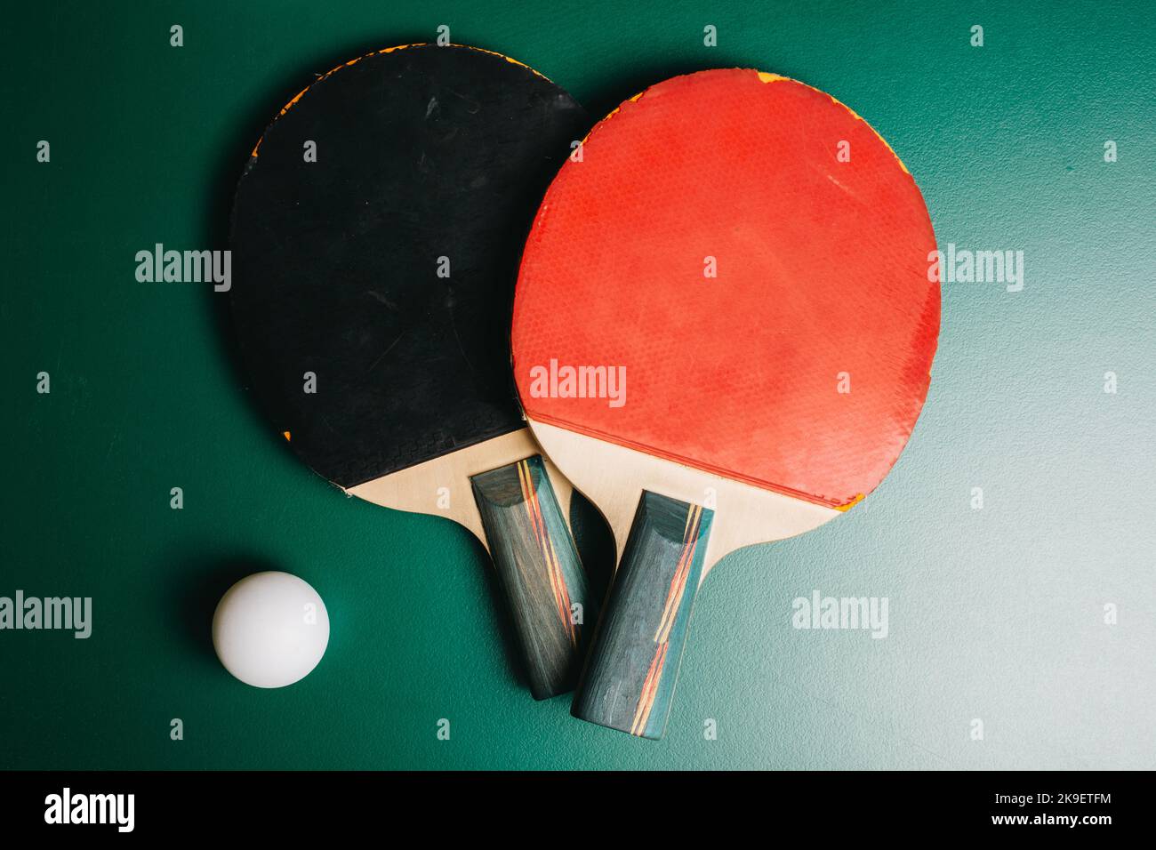 Zwei Tischtennisschläger und ein Ball befinden sich auf dem grünen Spieltisch Stockfoto