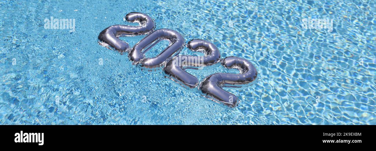 Silberne Foliennummern schweben auf blauem, sauberem Poolwasser, festliches Dekor Stockfoto
