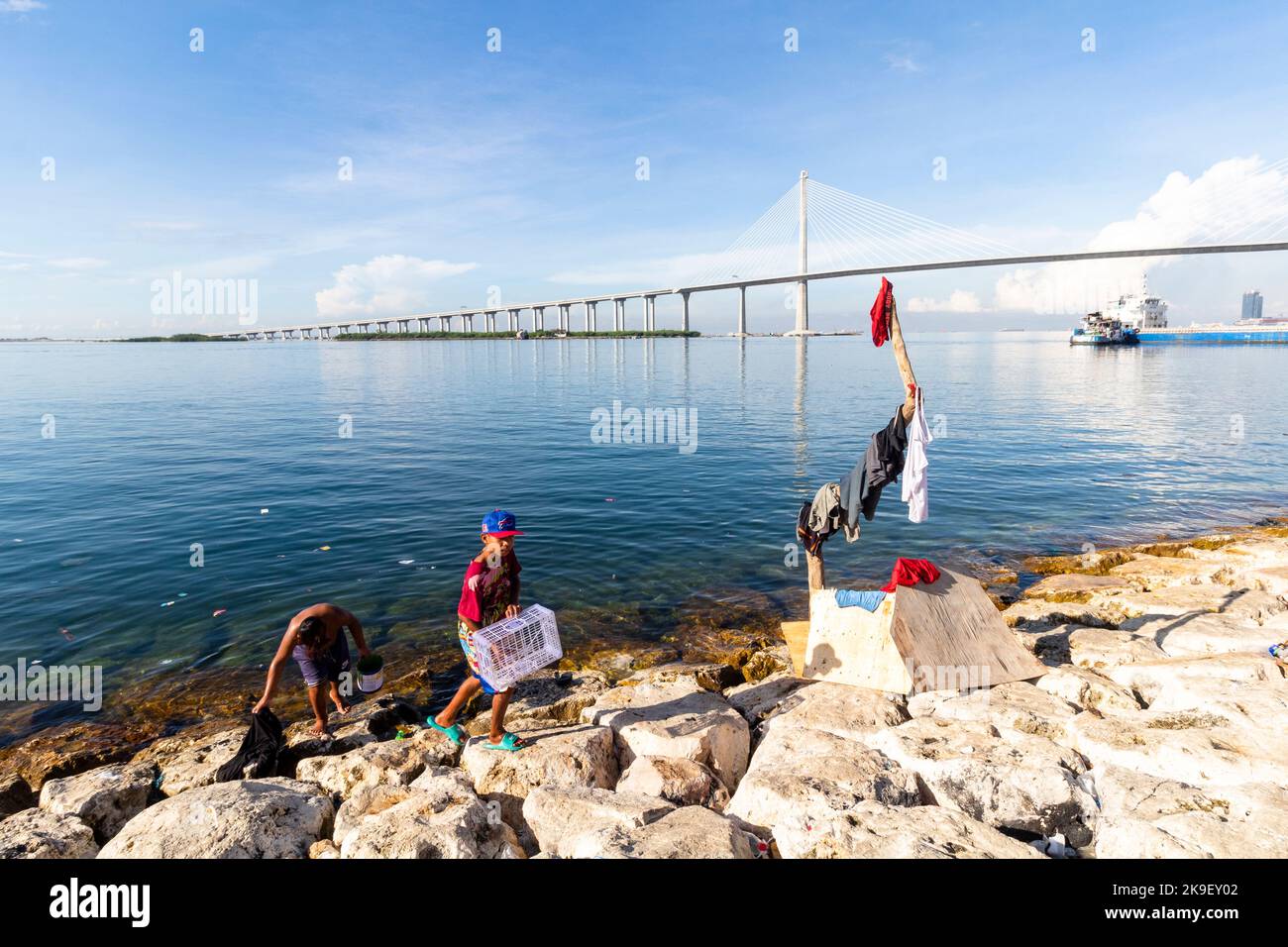Männer am Meer mit dem Cebu-Cordova Link Expressway im Hintergrund Stockfoto