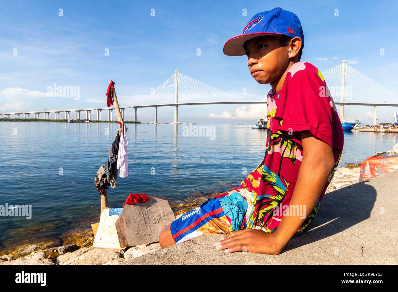 Porträt eines Jungen mit dem Cebu-Cordova Link Expressway im Hintergrund Stockfoto