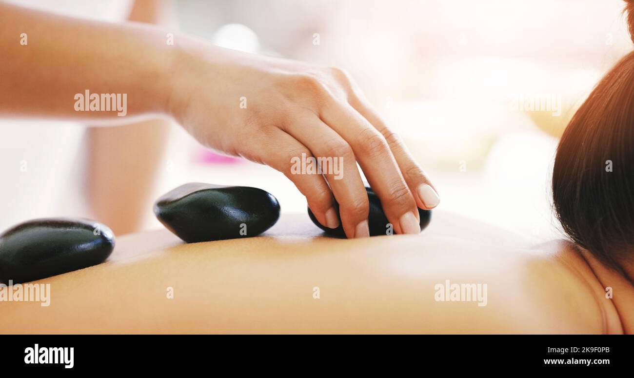 Diese Steine haben heilende Eigenschaften. Eine junge Frau bekommt eine Massage mit heißen Steinen in einem Spa. Stockfoto