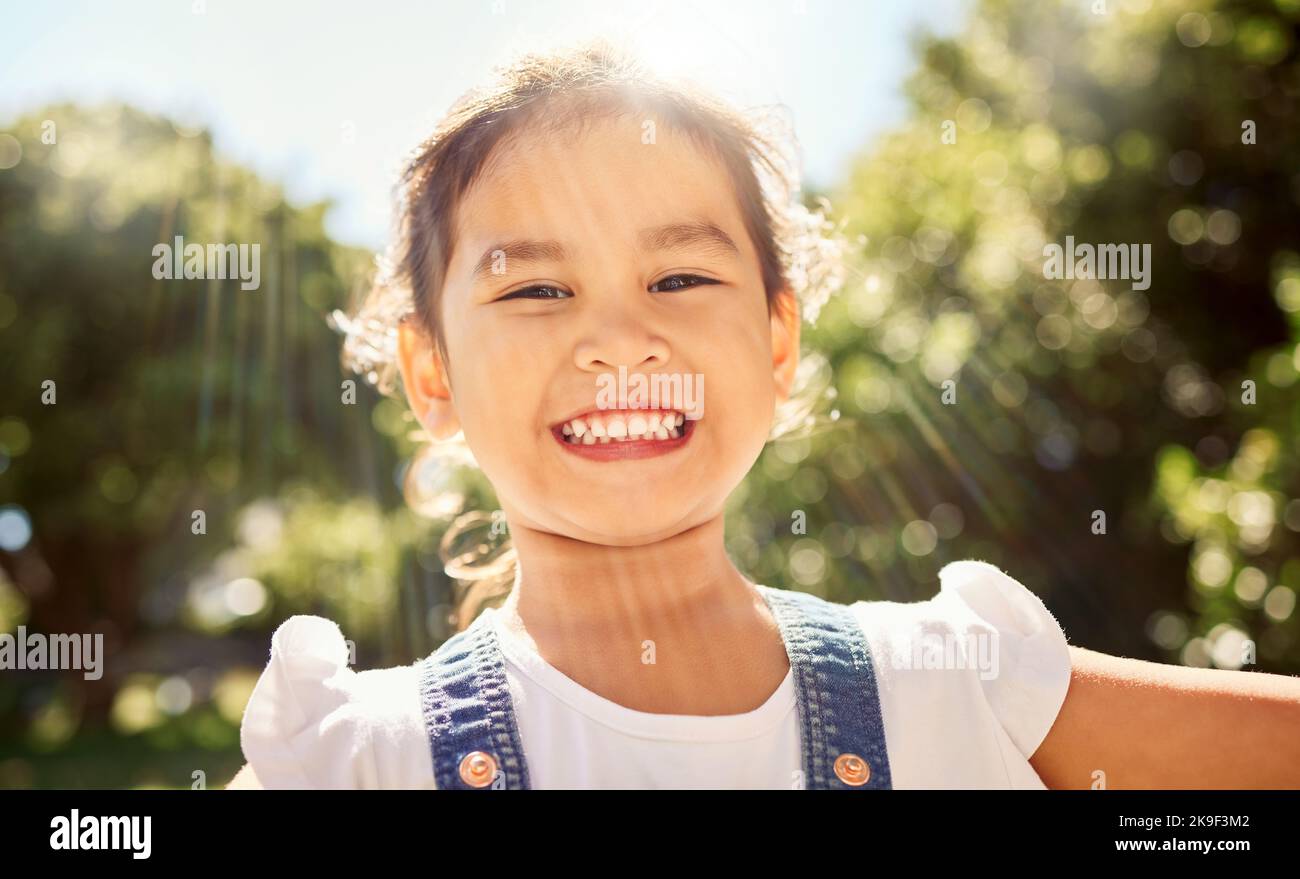 Sommer, Sonnenschein und Porträt des asiatischen Kindes im Park lächeln im Gesicht, spielen und die Natur genießen. Glück, Freude und junge Mädchen, die Spaß im Freien Stockfoto