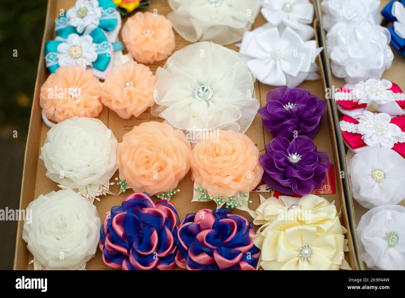 Blumen aus Haargewebe. Haarspangen in verschiedenen Farben. Stoffprodukte für die Dekoration. Rosen aus Stofflappen. Stockfoto