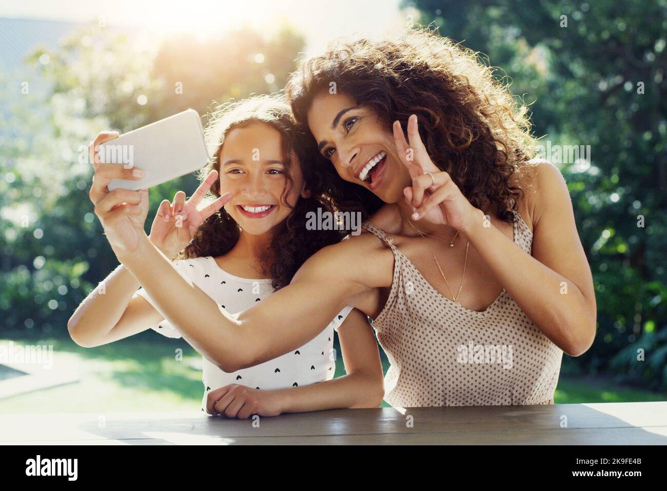 Wir haben immer die besten gemeinsamen Zeiten. Eine junge Mutter und ihre Tochter machen tagsüber gemeinsam Selfies im Park. Stockfoto