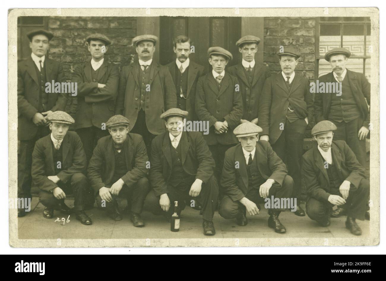 Ursprüngliche Postkarte aus dem frühen 20. Jahrhundert von Männern der Arbeiterklasse außerhalb eines Pubs, einige breite und einige dünnere Kragen so um 1912, viele flache Kappen, Lookalikes. Es gibt eine Flasche Bier neben einem Mann, also ist es ein Junggesellenabschied, Arbeit tun, Beförderung, Abschluss Lehre, Geburtstagsfeier, Neuer Vater. Wer weiß! GROSSBRITANNIEN Stockfoto