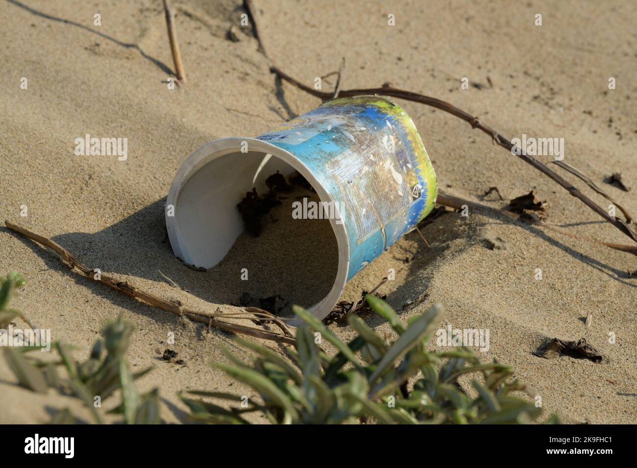 Verschmutzung durch Plastik, Lebensmittelverpackungen zum Einmalgebrauch in Strandsand, schmutzige Umwelt, menschliche Aktivitäten, Umweltzerstörung, Container, Nahaufnahme, Tasse Stockfoto