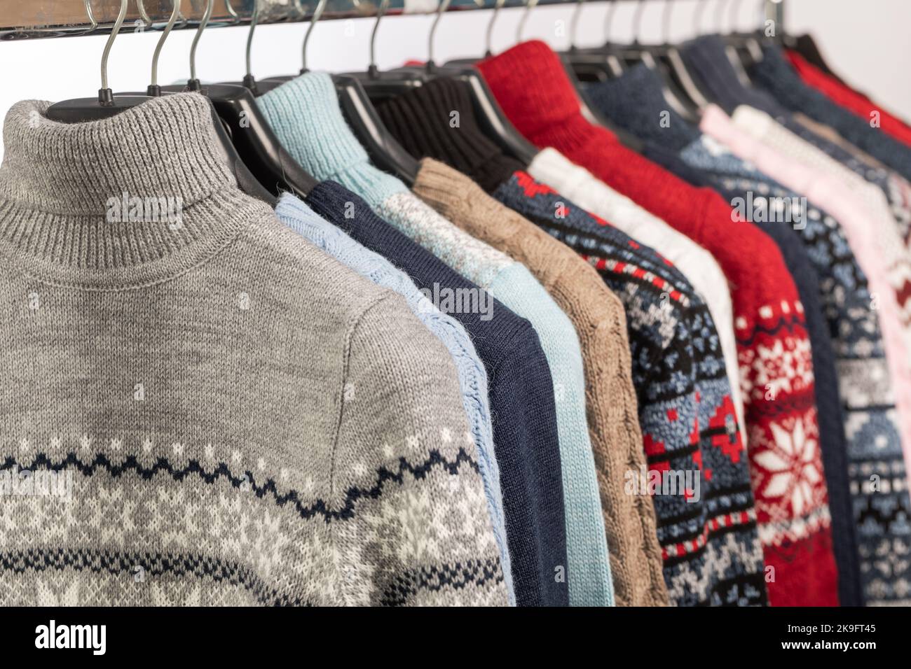 Verschiedene Vintage Rollkragenpullover und Pullover auf Kleiderständer in einem Gebrauchtwarengeschäft. Thrifting und Nachhaltigkeit im Bekleidungskonzept Stockfoto