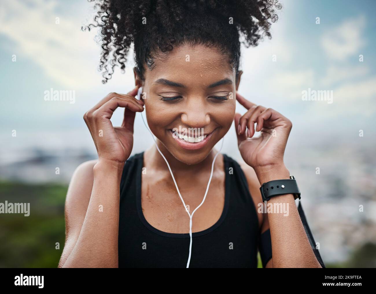 Das ist die Melodie, die mich in Bewegung hält. Eine sportliche junge Frau, die Musik hört, während sie im Freien trainiert. Stockfoto