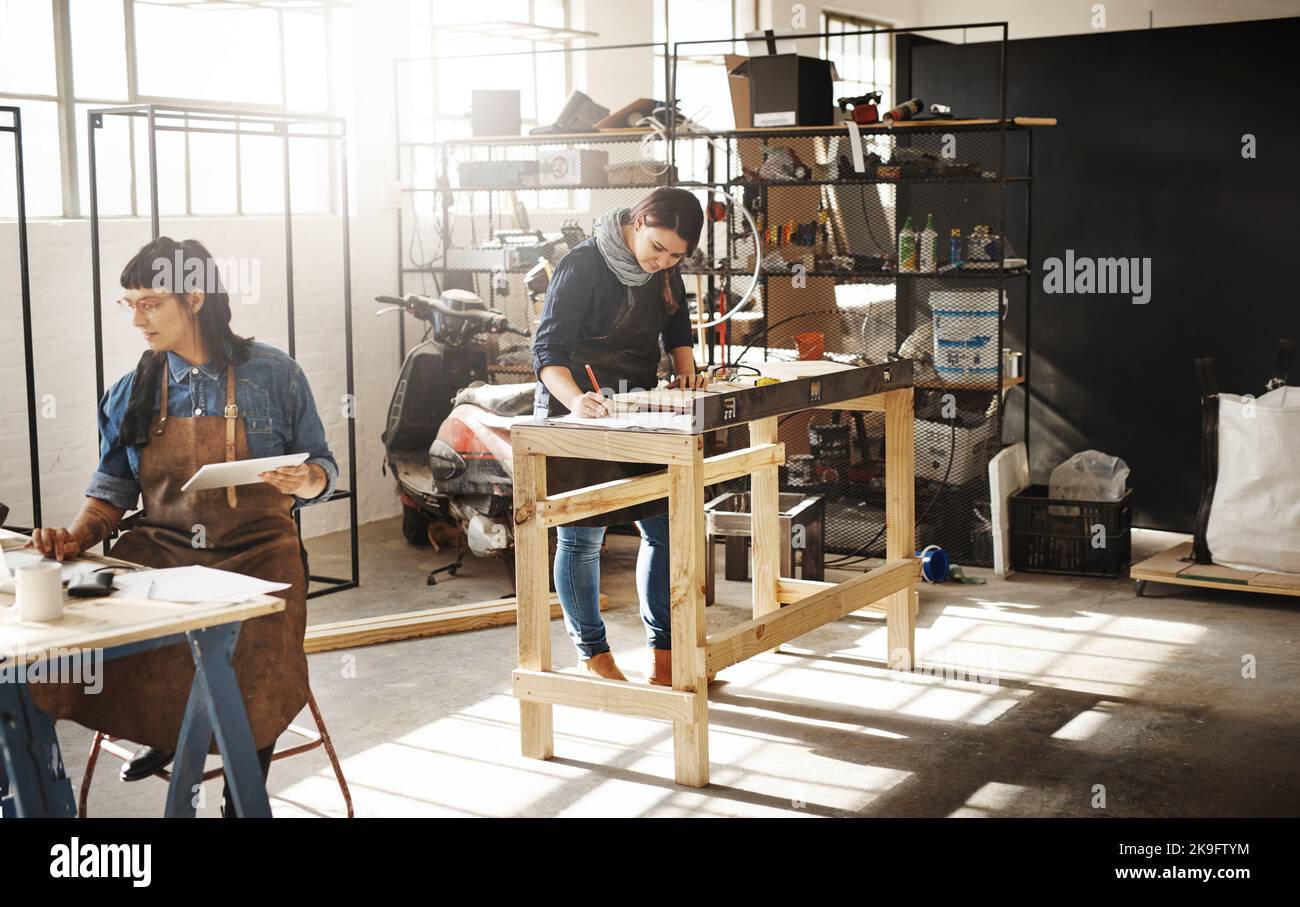Hier schaffen sie. Zwei attraktive junge kreative Kunsthandwerkerinnen, die in ihrer Werkstatt arbeiten. Stockfoto