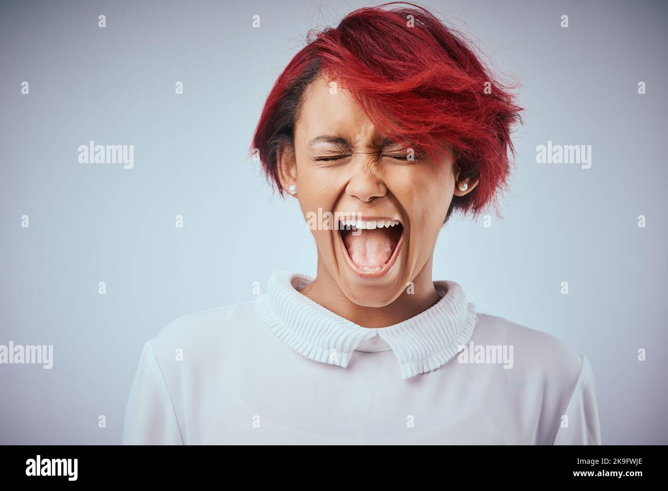 Ich wurde nicht dazu gemacht, subtil zu sein. Studioaufnahme einer attraktiven jungen Frau, die vor grauem Hintergrund schreit. Stockfoto