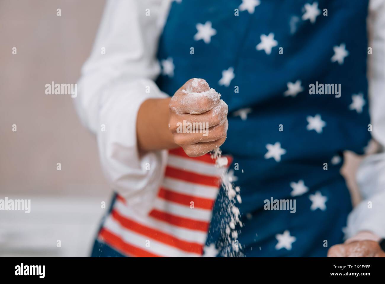 Die junge Hausfrau knetet mit ihren Händen auf einer Schürze Teig. Stockfoto