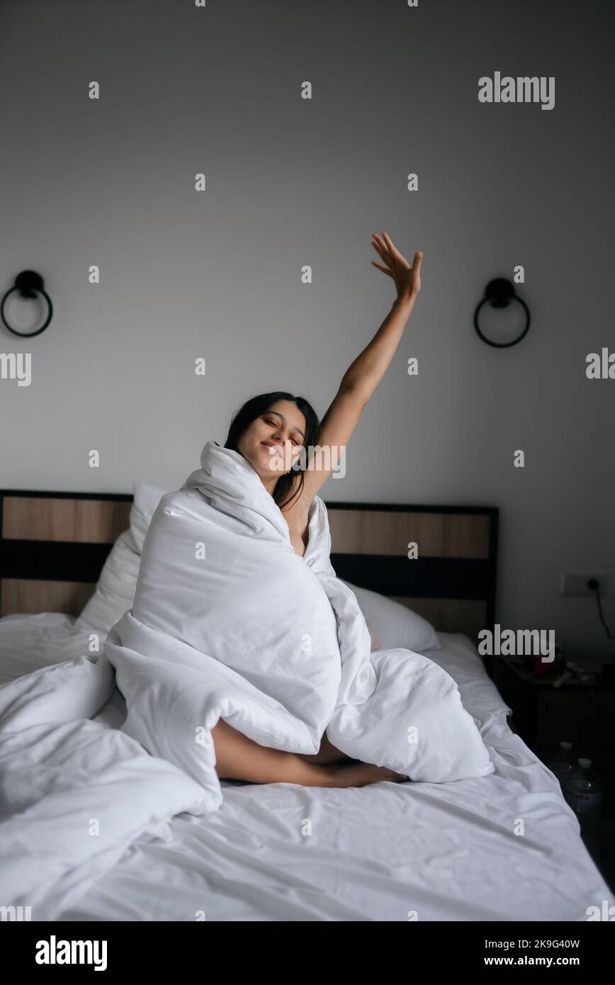 Faule Frau in weiche Decke gewickelt sitzen in einem gemütlichen Bett Stockfoto