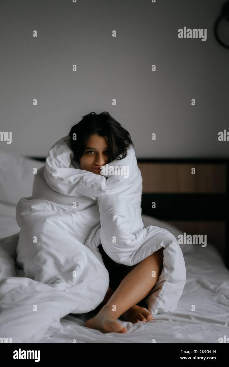 Faule Frau in weiche Decke gewickelt sitzen in einem gemütlichen Bett Stockfoto