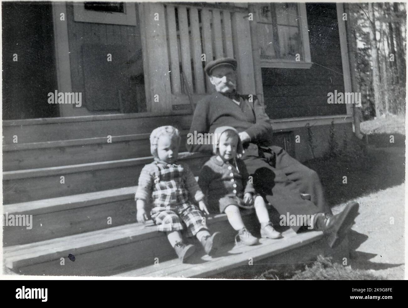 Letzten Frühling/Sommer in Långsjön. Auf Långsjötrappen sitzt der alte Großvater per Andersson mit den Enkelkindern Lillemor und Ad. Stockfoto