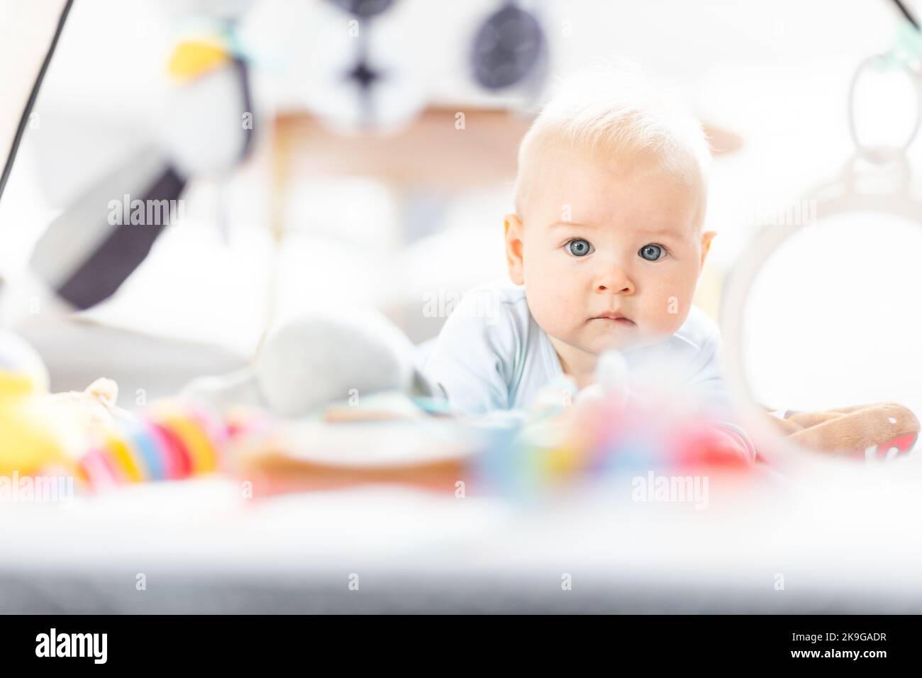 Niedlicher Baby Junge spielt mit hängendem Spielzeug Bogen auf Matte zu Hause Baby-Aktivität und Spielzentrum für die frühe Säuglingsentwicklung. Baby spielt zu Hause Stockfoto