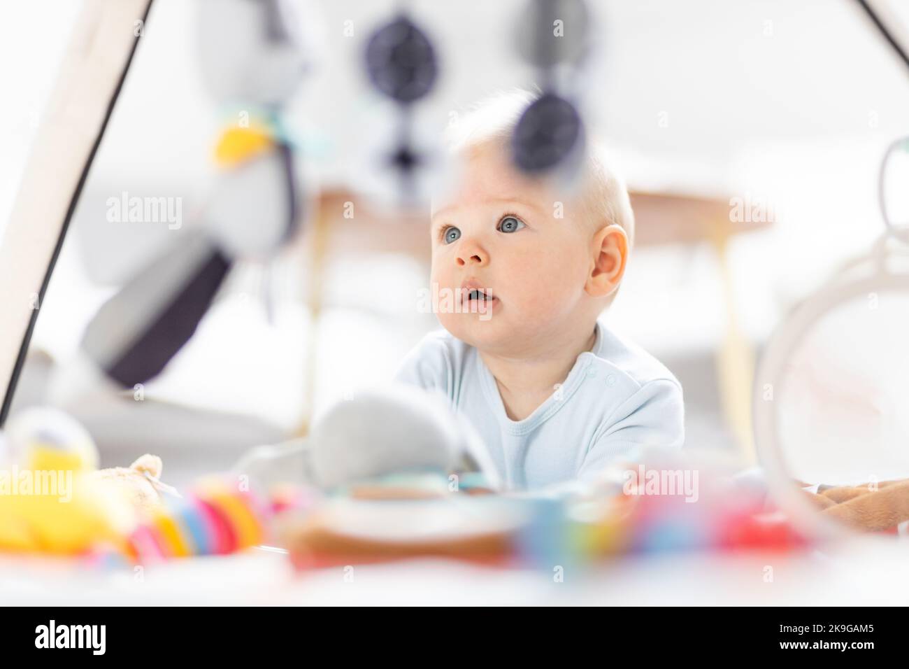 Niedlicher Baby Junge spielt mit hängendem Spielzeug Bogen auf Matte zu Hause Baby-Aktivität und Spielzentrum für die frühe Säuglingsentwicklung. Baby spielt zu Hause Stockfoto