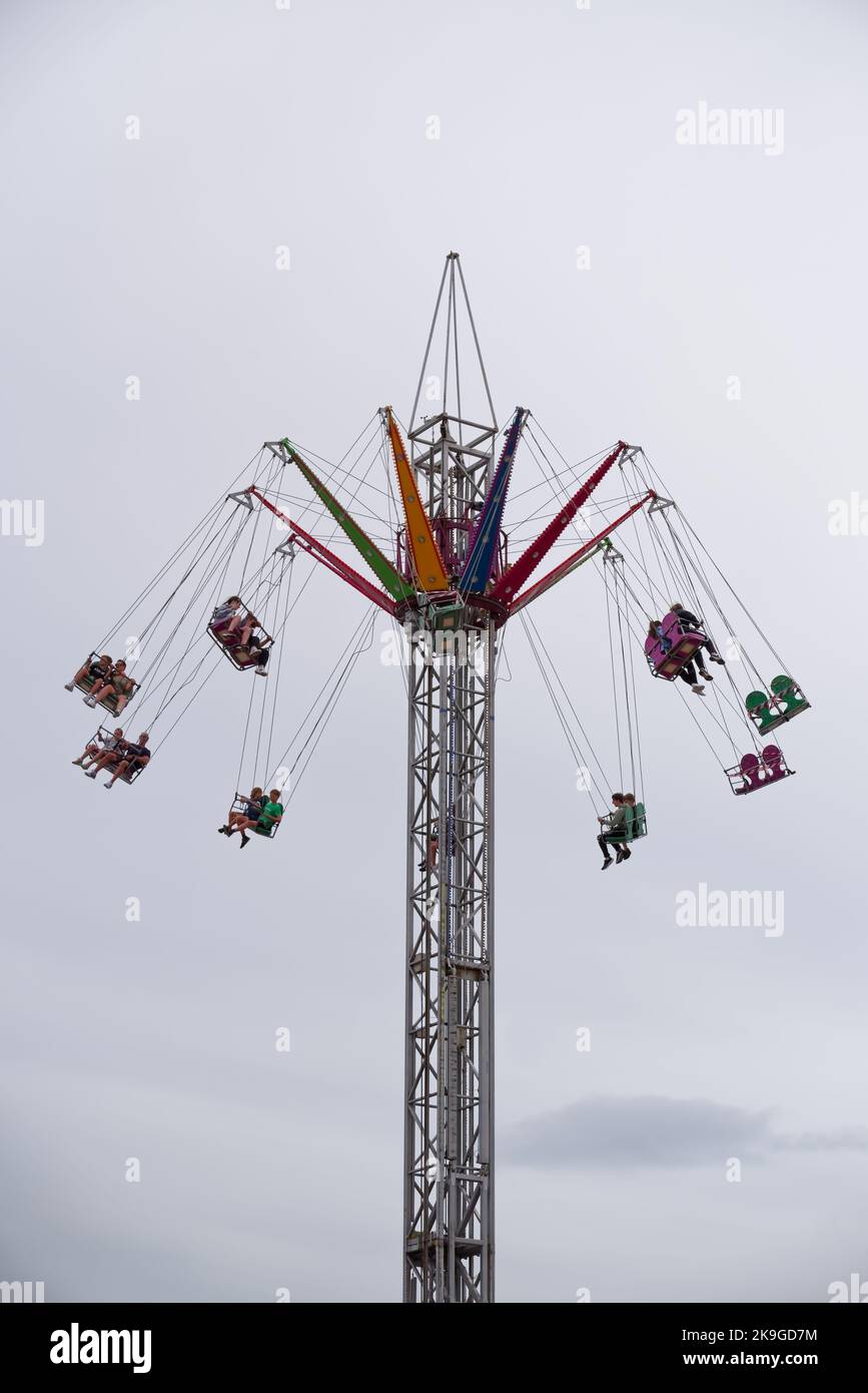 Auf der jährlichen Seafront Fun Fair in Bray, Irland, können Sie auf der Drop Tower Fairground Ride die Abenteuerlustigen sehen. Wolkiger Sommertag. Vertikale Aufnahme. Stockfoto