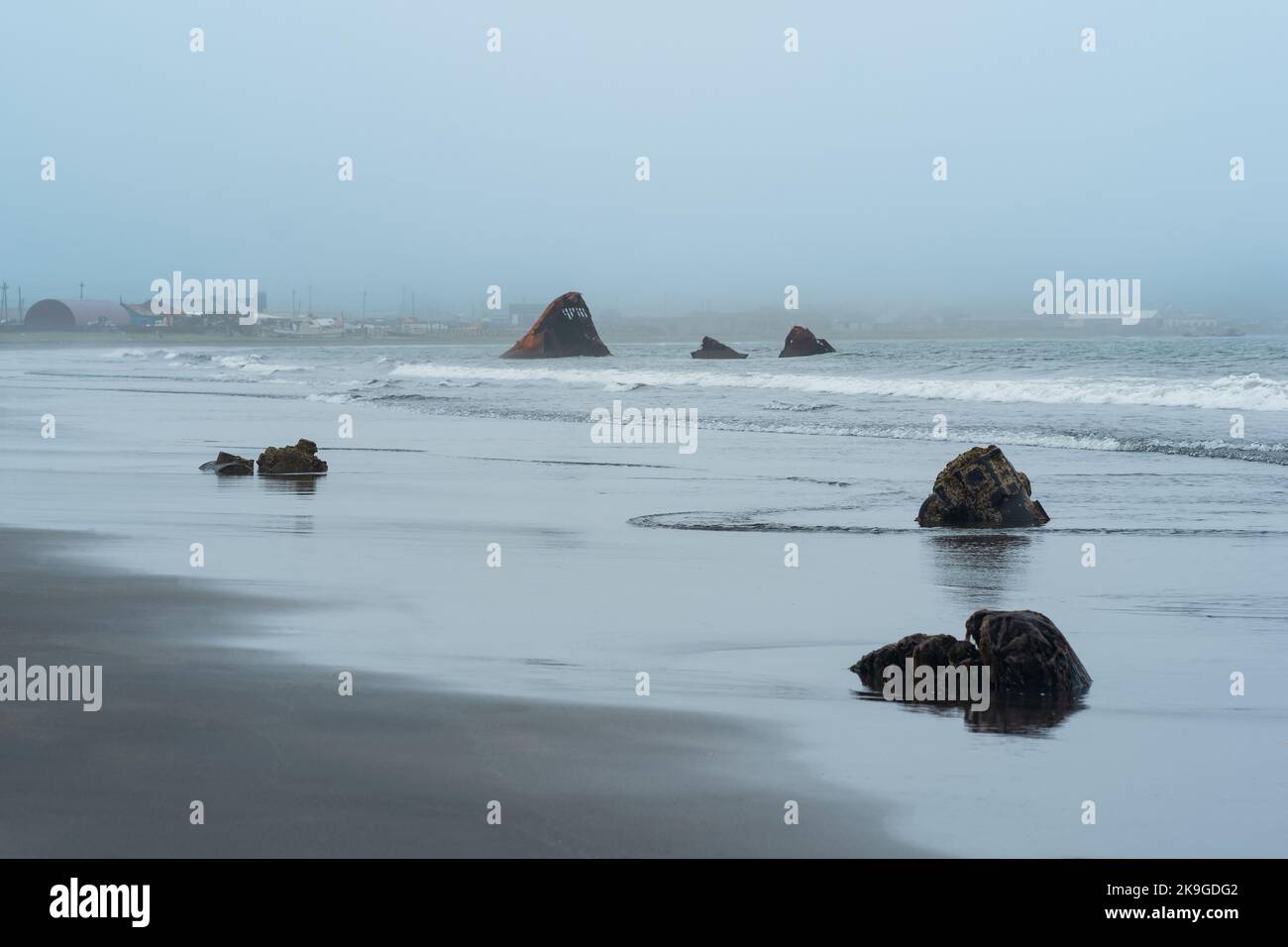 Neblige Küste der Insel Kunashir mit rostigen Schiffswracks während der Bewölkung Stockfoto