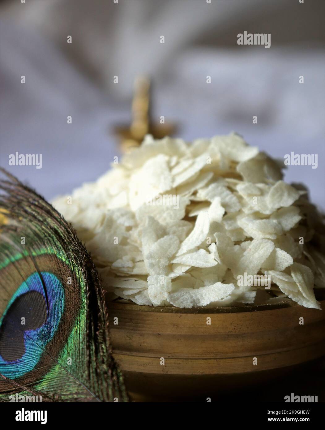 Nahaufnahme von rohem Poha/geschlagenem Reis/abgeflachtem Reis/Messingöllampe/Pfauenfeder-Krishna Janmashtami Stockfoto